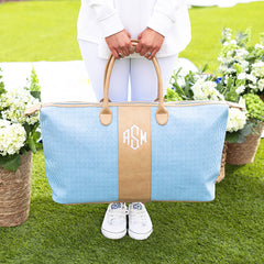Girl holding navy seersucker weekender on grass