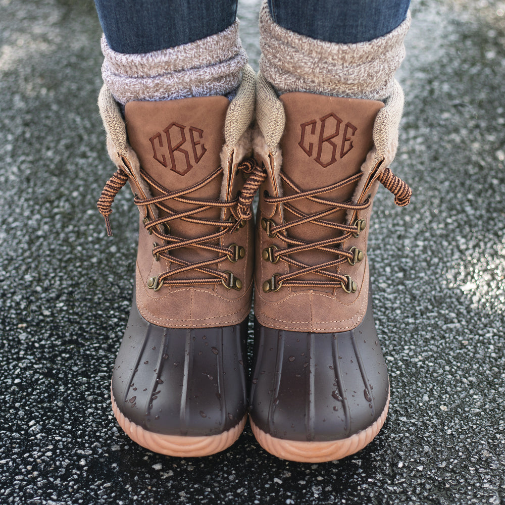 brown explorer monogrammed duck boots on wet pavement