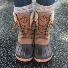 brown explorer monogrammed duck boots on wet pavement