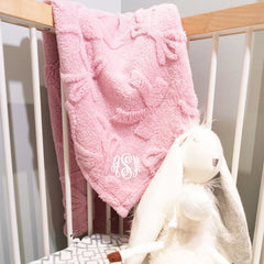 pink baby blanket in corner of crib