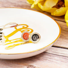 gold disc monogrammed earrings on jewelry tray and yellow flowers