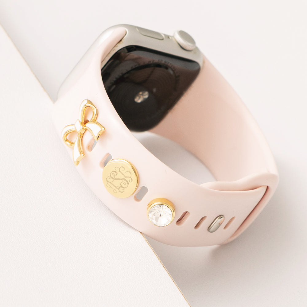 up close of monogrammed bow smartwatch charm set in gold on watch
