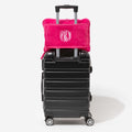 monogrammed travel blanket pillow in hot pink on suitcase