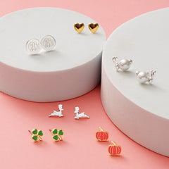 monogrammed year round earring set on white discs and pink paper