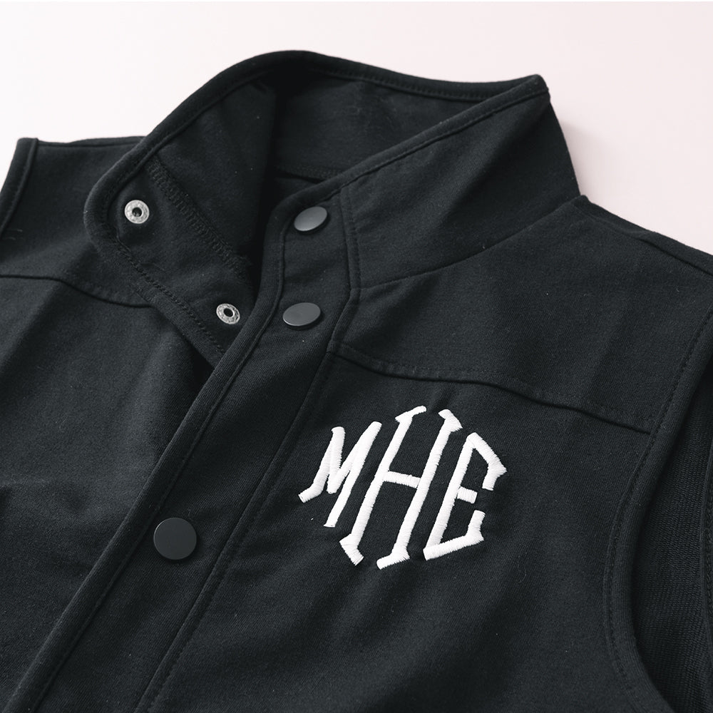 close up of buttons on black monogrammed sweatshirt vest