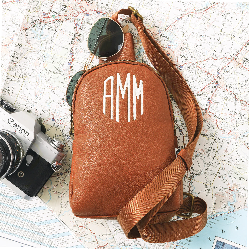 brown sling bag on top of map