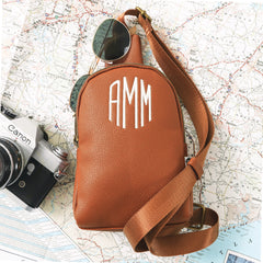 brown sling bag on top of map
