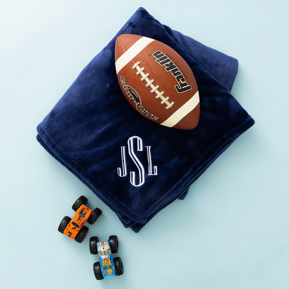 navy plush blanket with football and monster trucks on blue paper