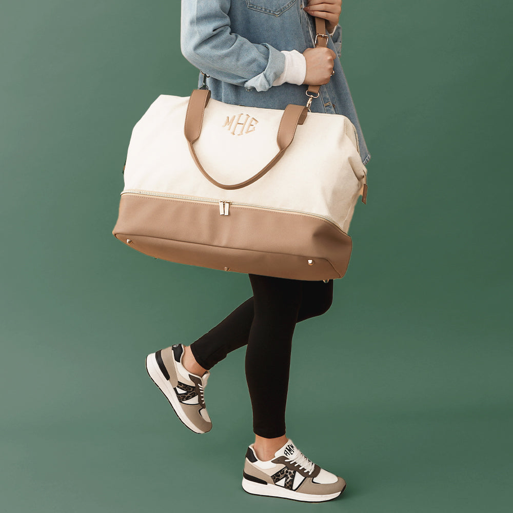 ivory canvas weekender on shoulder with green background