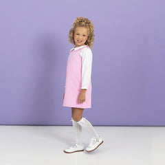 Girl wearing jumper dress with collared shirt side view