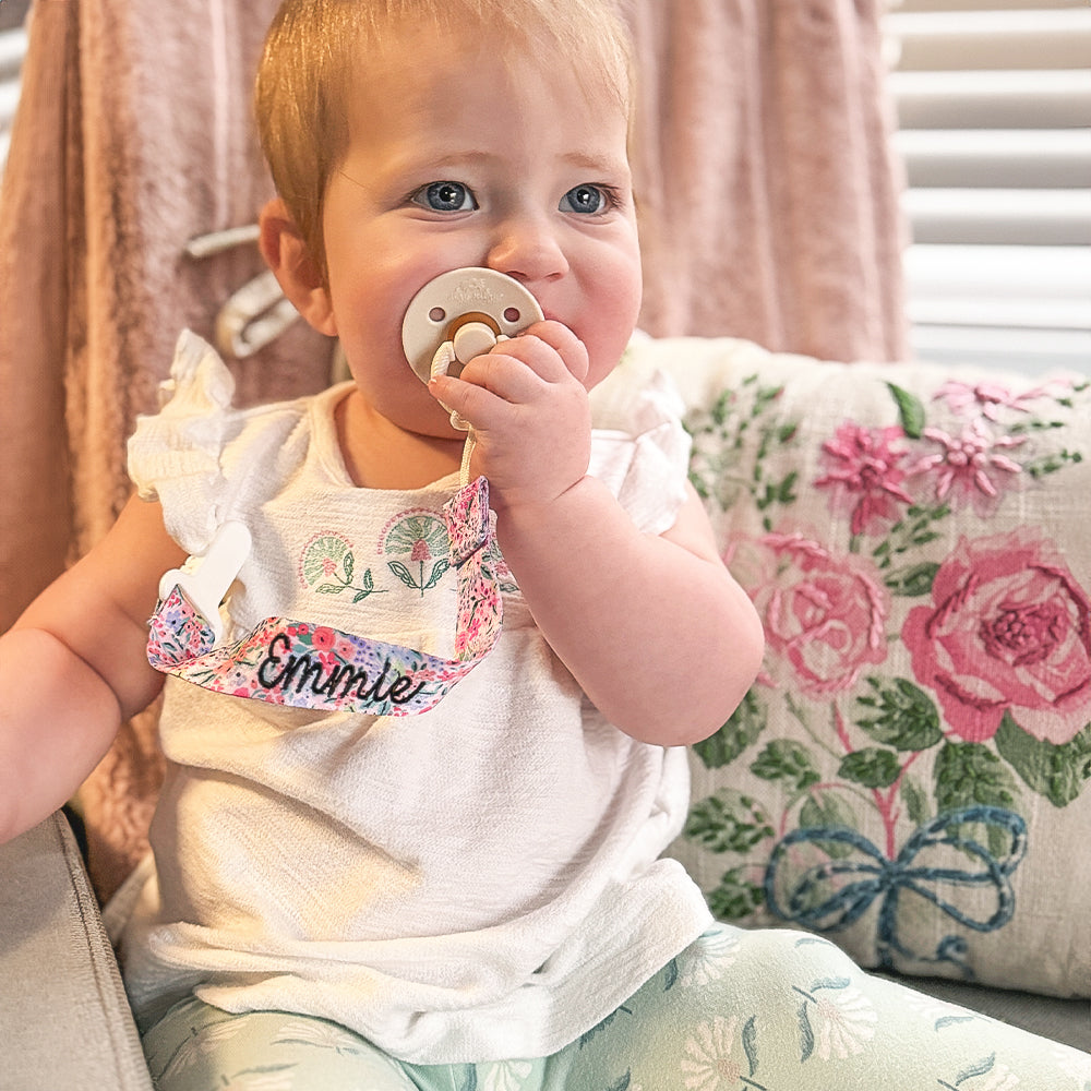 baby with monogrammed paci clip in coral floral