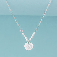 silver pearl monogrammed necklace on blue background