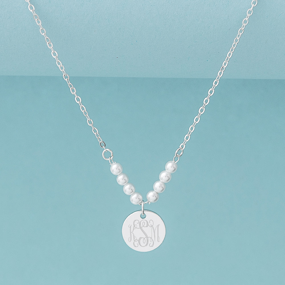 silver pearl monogrammed necklace on blue background