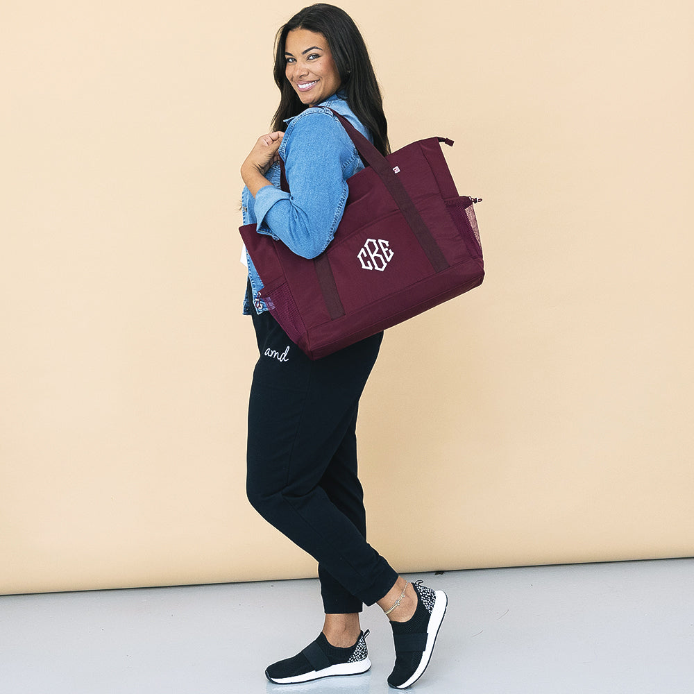 girl carrying monogrammed carry on tote in burgundy