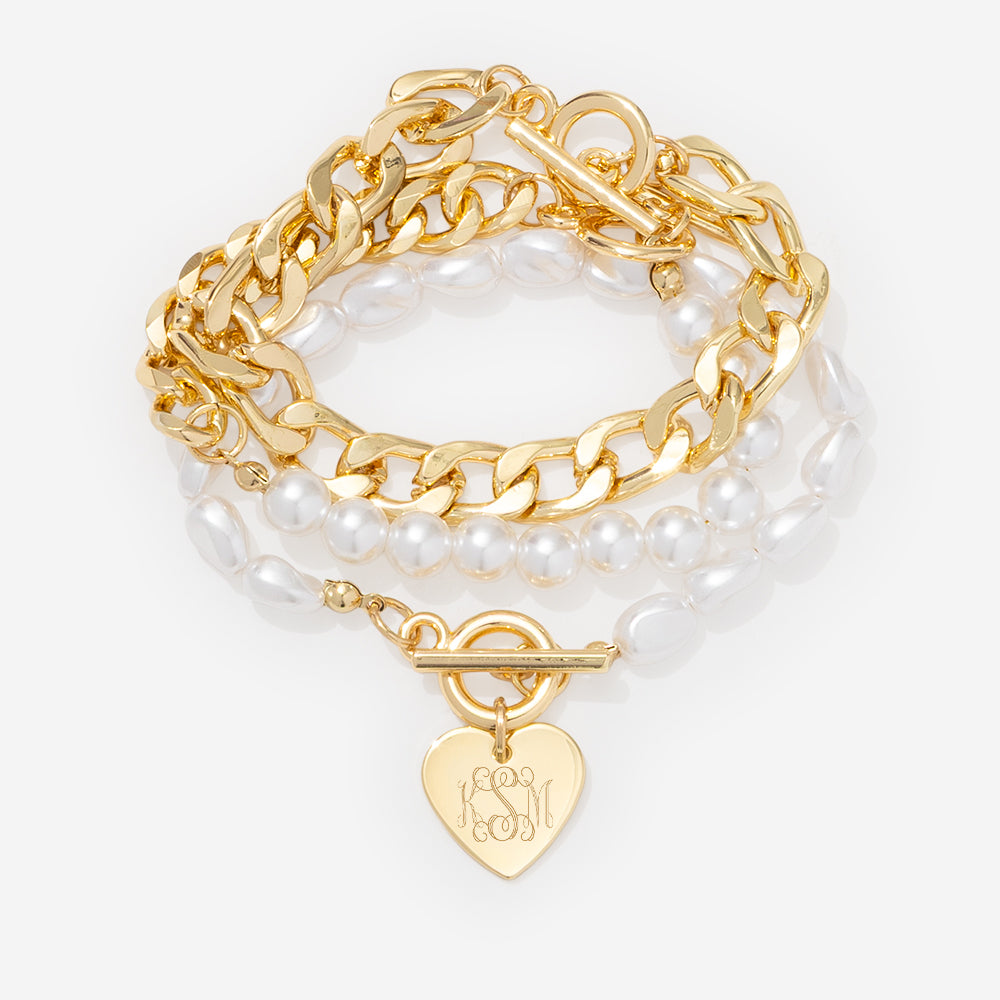 Gold chain bracelet with heart-shaped tag on a white background