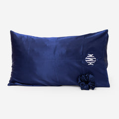 Navy blue satin pillowcase with a scrunchie on a white background