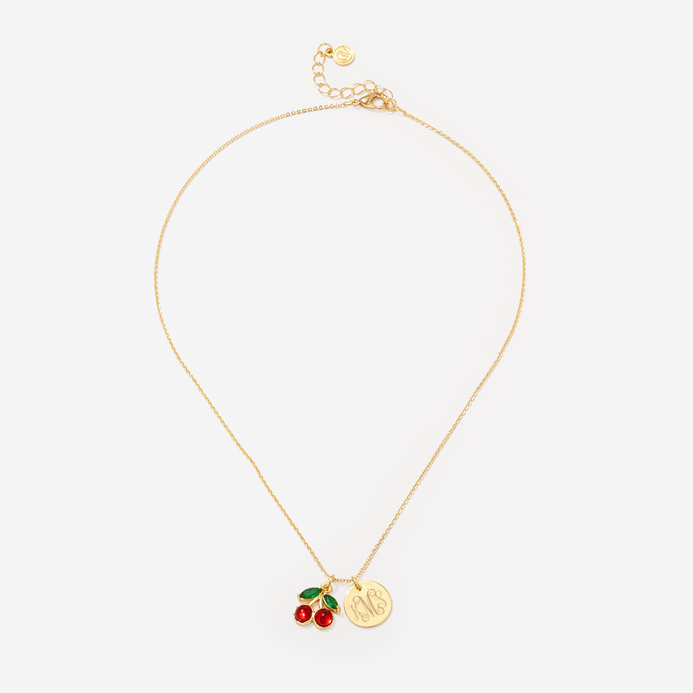 Gold necklace with cherry and coin charm on a white background