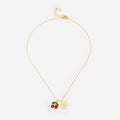 Gold necklace with cherry and coin charm on a white background