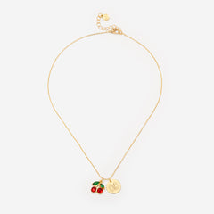 Gold necklace with cherry and coin charm on a white background