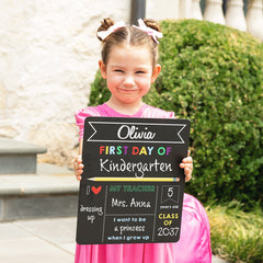 elle holding back to school chalkboard filled out