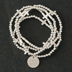 close up of monogrammed silver cross bracelet stack