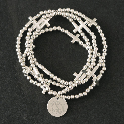 close up of monogrammed silver cross bracelet stack