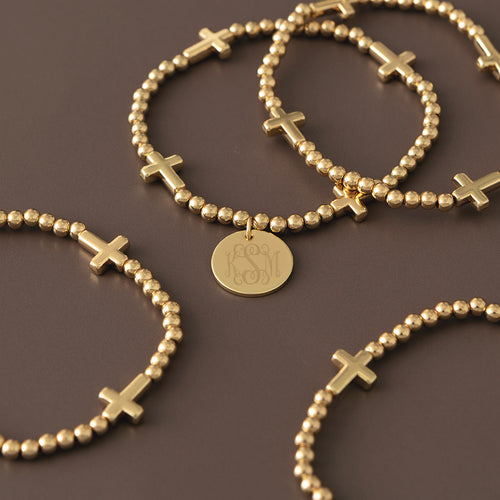 gold monogrammed cross bracelet stack scattered