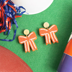 orange gameday bow earrings on green background