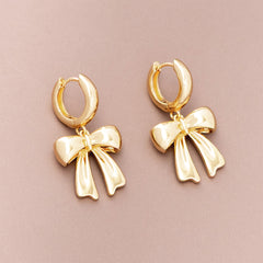 bow huggie hoop earrings on brown background