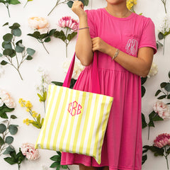 woman holding yellow and white striped tote bag