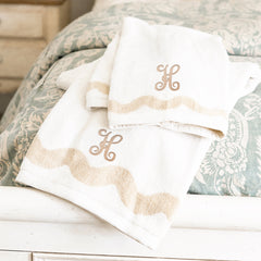 bath towel set on bed with tan interlocking initial