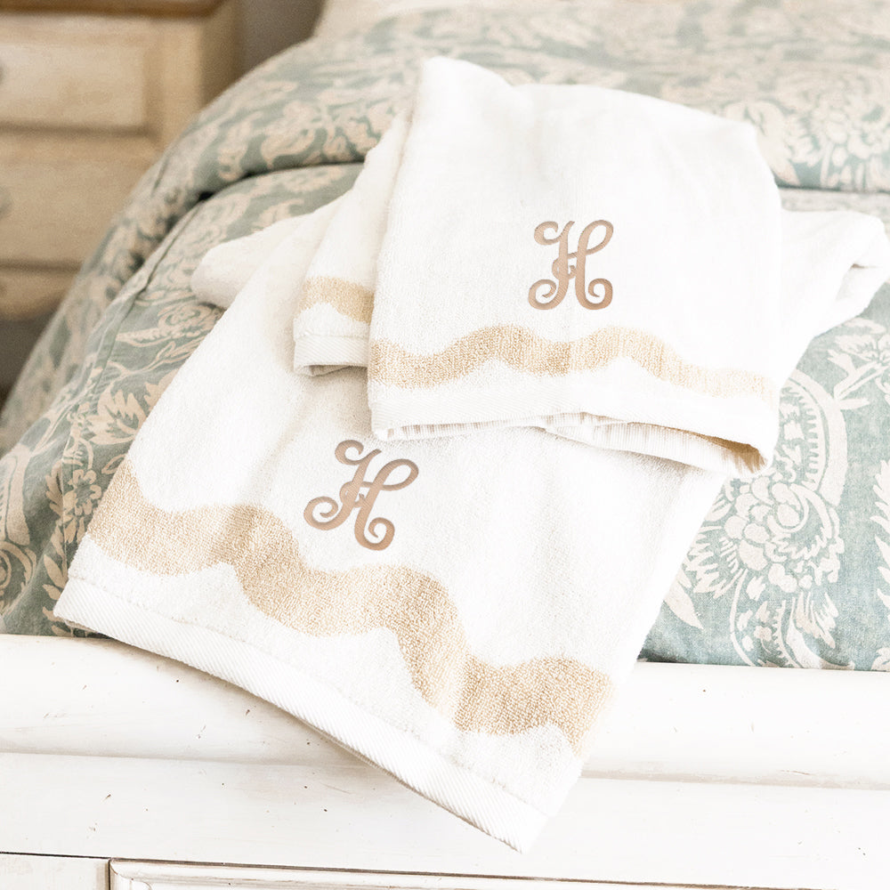 bath towel set on bed with tan interlocking initial