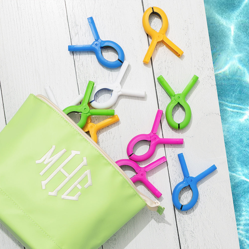 Colorful beach chair towel clips on a white surface with a green zip pouch.