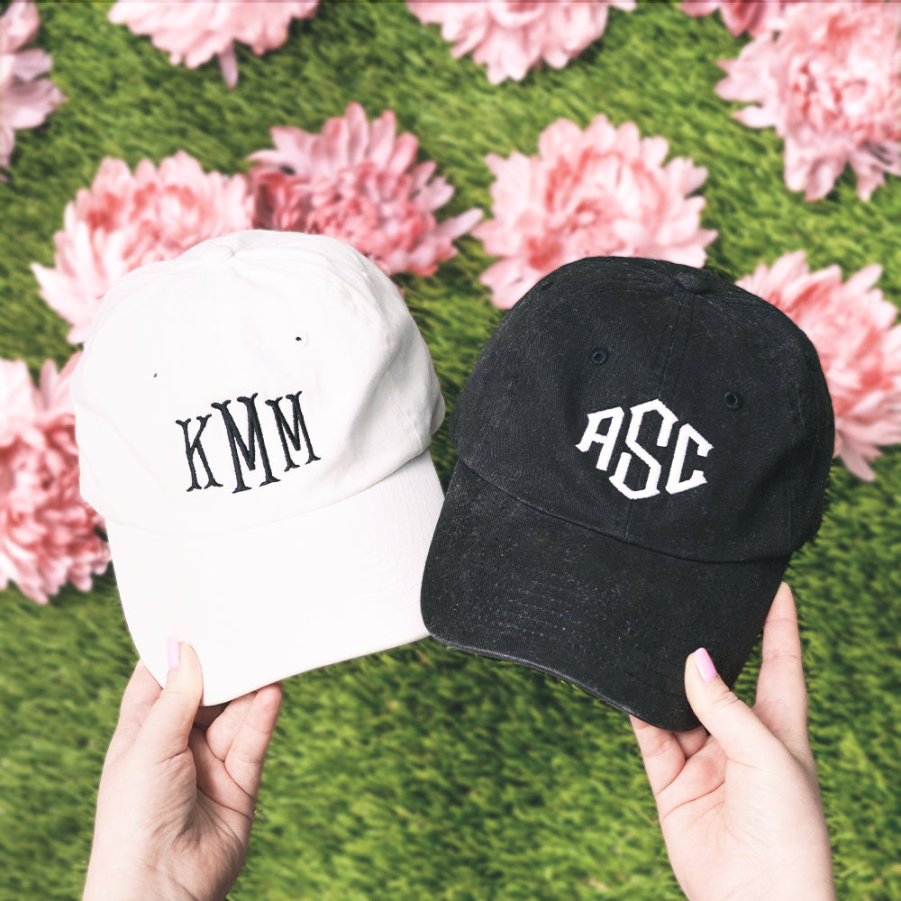 Two caps, one white and one black, held against a floral background.