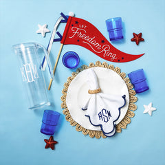 Decorative home items including a plate with personalized napkin, flag, and tumblers on a blue background