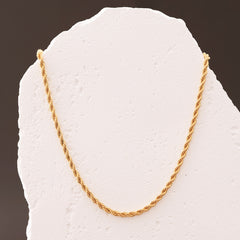 Gold chain on a textured white surface with a dark background