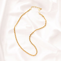 Gold chain necklace on a light pink background