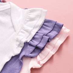 Close-up of ruffled sleeves in white, purple, and pink on a pink background