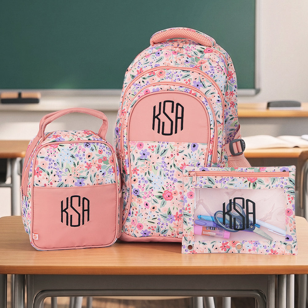 coral floral monogrammed backpack lunch box and binder pouch on students desk in classroom