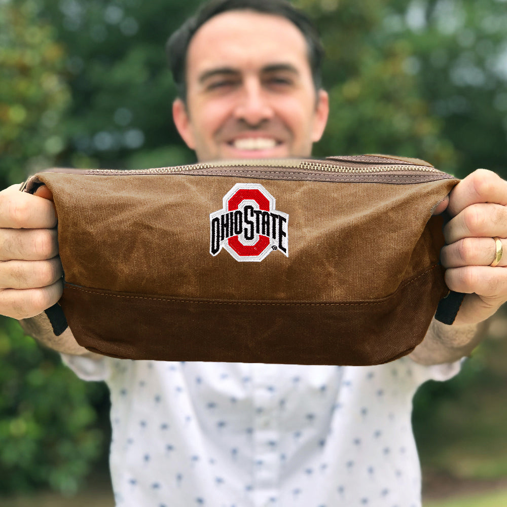 man holding ohio state waxed canvas dopp kit