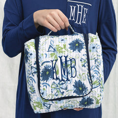 girl carrying indigo painted petals monogrammed quilted hanging toiletry bag 
