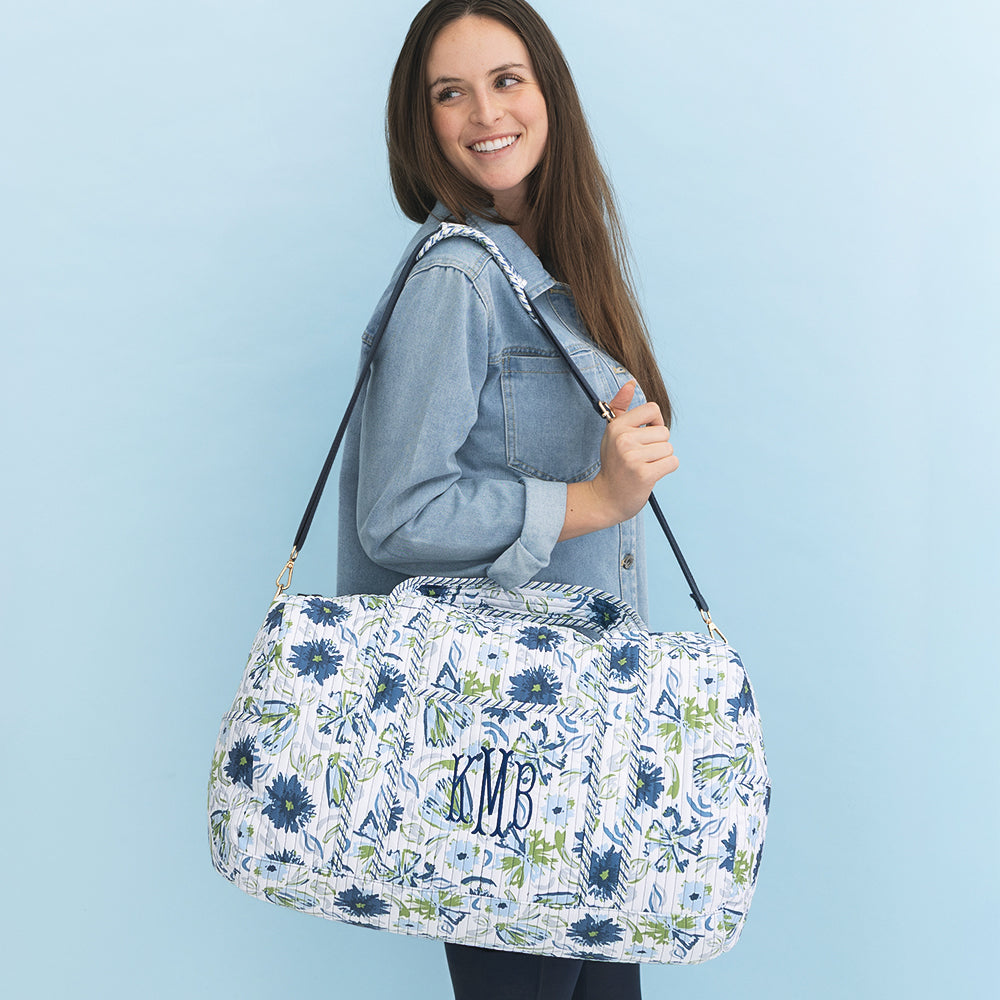 girl carrying indigo painted petals monogrammed quilted weekender 