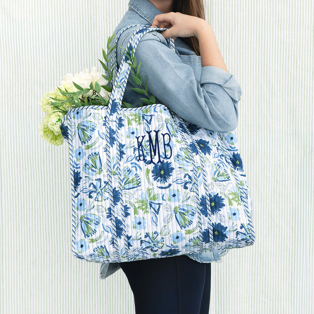 girl carrying monogrammed quilted tote bag in indigo painted petals on green seersucker background 