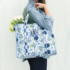 girl carrying monogrammed quilted tote bag in indigo painted petals on green seersucker background 