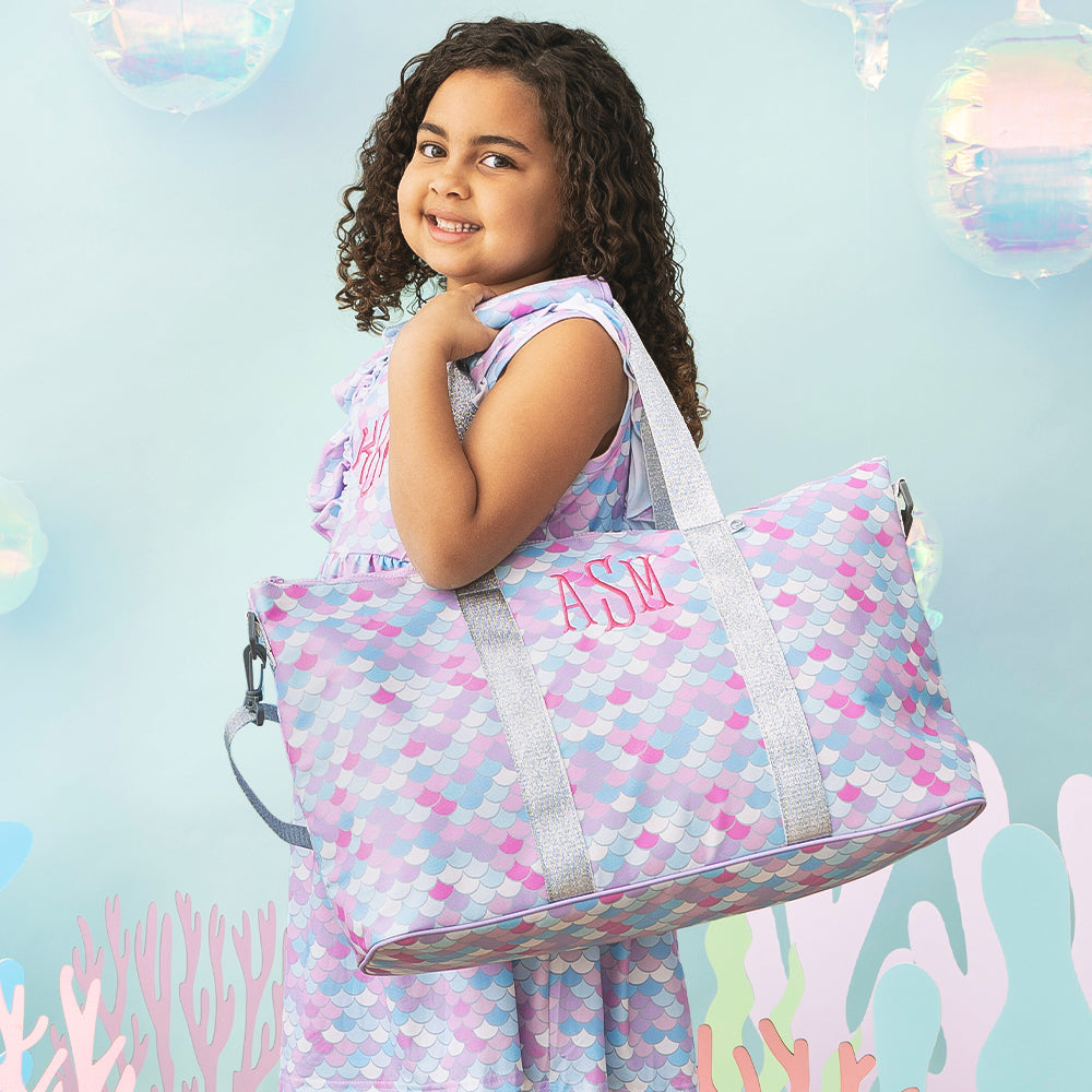 girl wearing mermaid ruffle dress with matching monogrammed kids weekend bag
