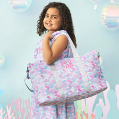 girl wearing mermaid ruffle dress with matching monogrammed kids weekend bag