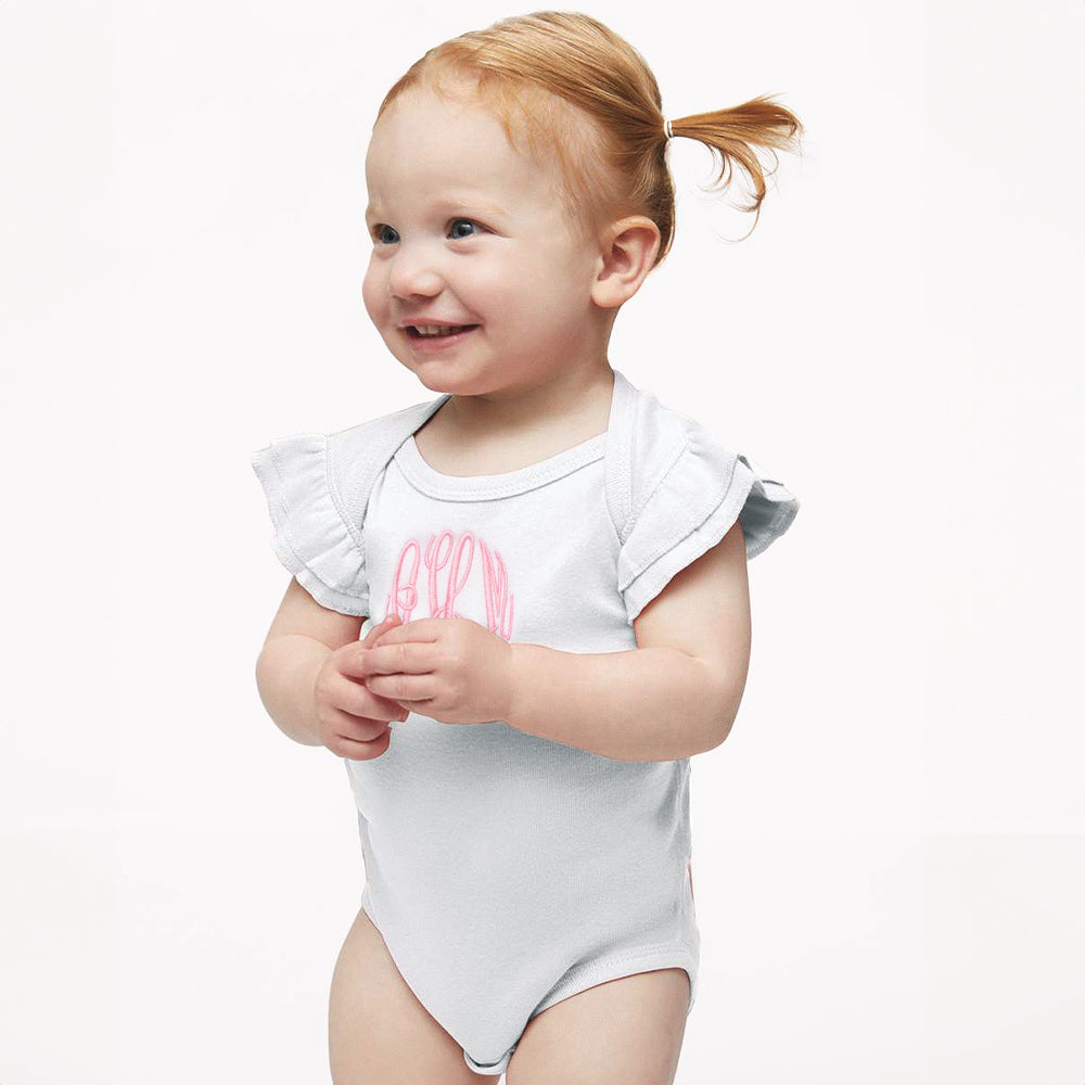 Baby wearing a white onesie with pink lettering on a white background