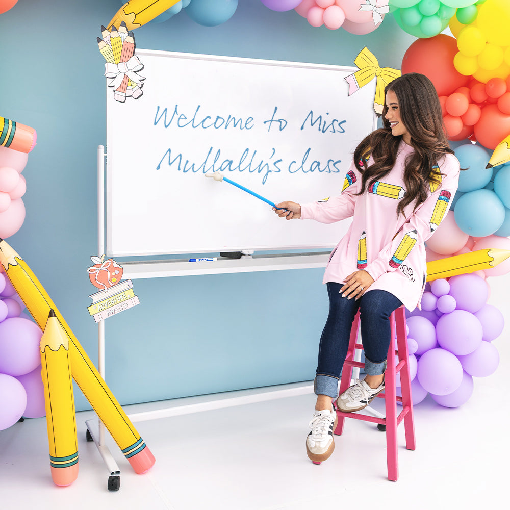 girl wearing personalized sequin teacher sweatshirt in pink pencils with white board