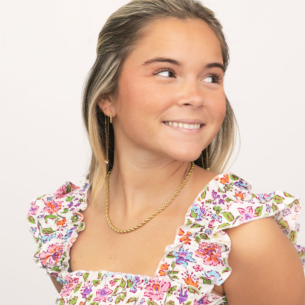 Woman wearing a floral dress with ruffled sleeves and a gold chain necklace