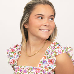 Woman wearing a floral dress with ruffled sleeves and a gold chain necklace